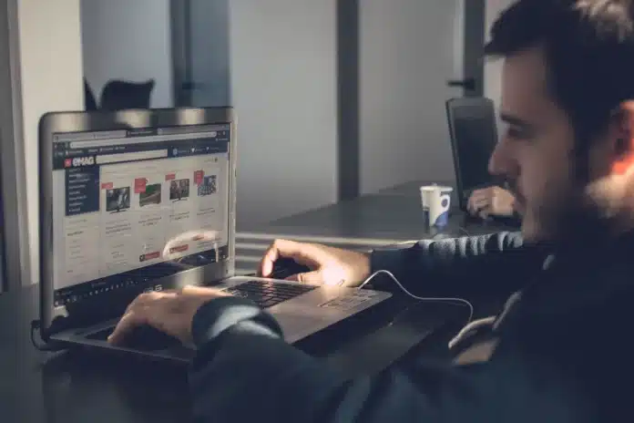 Mains tapant sur un clavier d'ordinateur portable avec un tableau de bord e-commerce affiché à l'écran