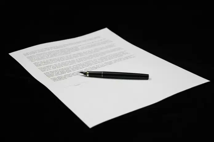 Mains tenant un document déchiré symbolisant la séparation des biens, avec dossiers financiers en arrière-plan