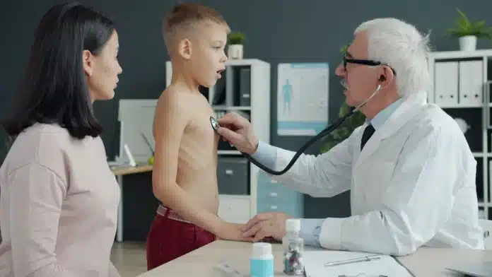 Professionnel examinant attentivement le bras d'un enfant pour détecter des signes de maltraitance