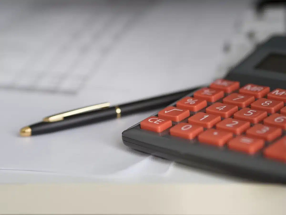 Personne examinant un bulletin et une calculatrice pour calculer des indemnités