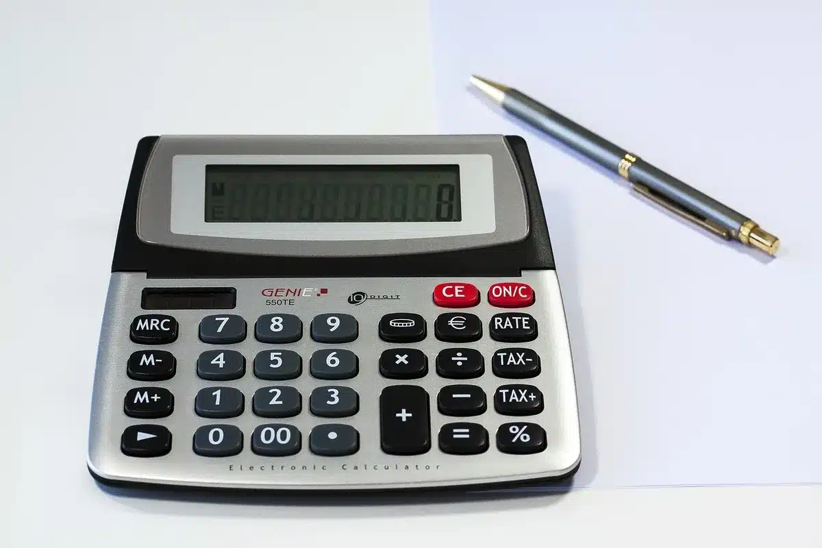 Calculatrice et documents financiers sur un bureau, calcul de rentabilité locative