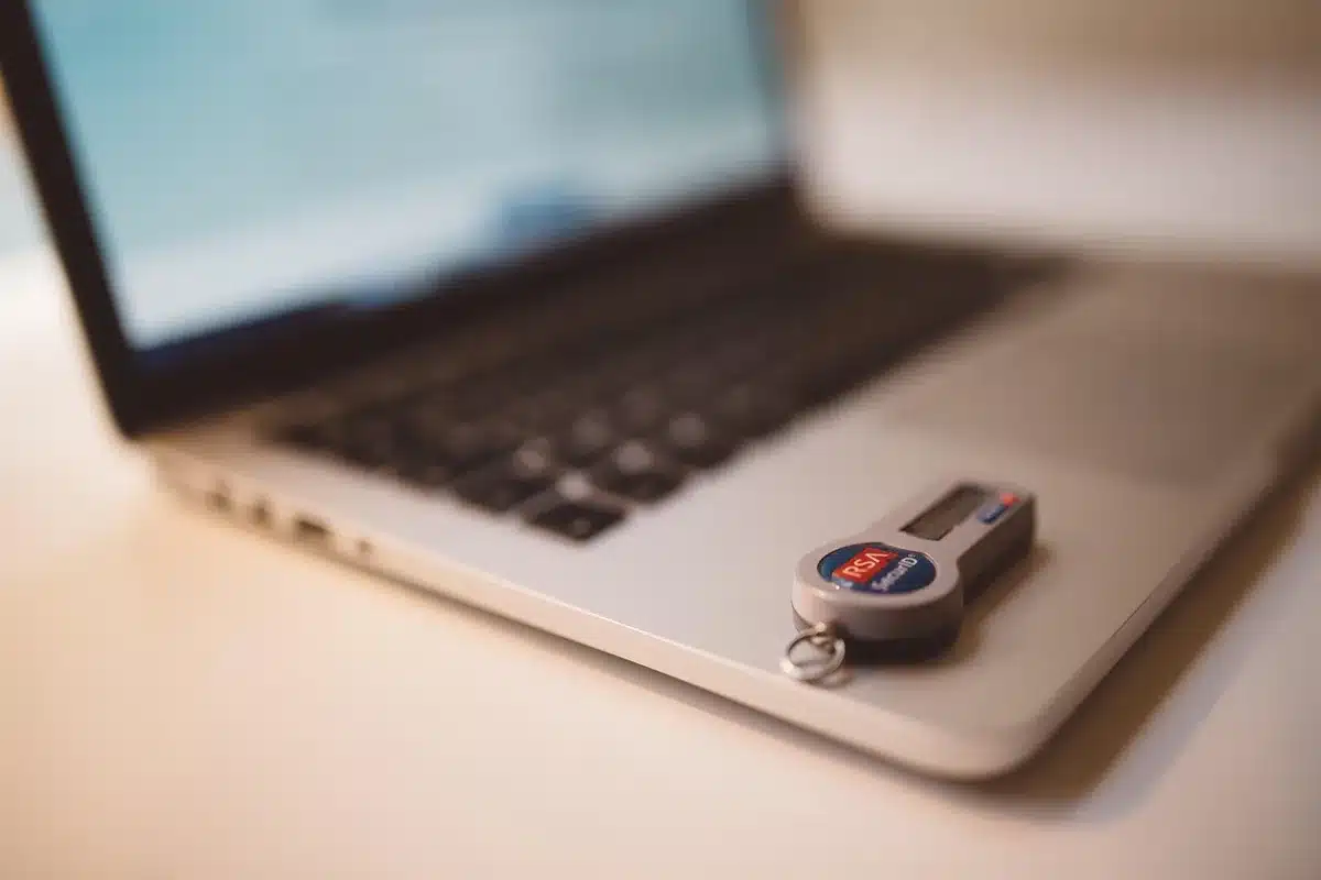 Main tenant une feuille avec l'ID d'un NFT et laptop en arrière-plan