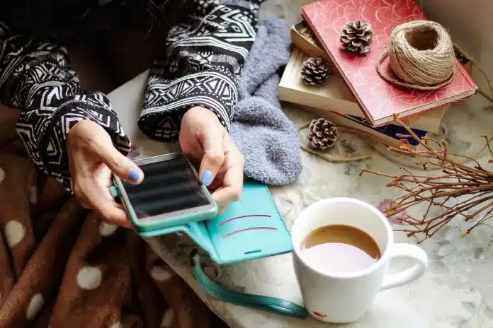 Bureau clair avec écran d'ordinateur, smartphone et carnet, mains anonymes en train de vérifier des données Bureau clair avec écran d'ordinateur, smartphone et carnet, mains anonymes en train de vérifier des données