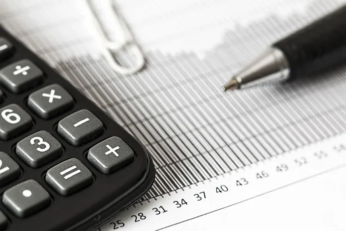 Table de cuisine en plein jour avec formulaires fiscaux, calculatrice et mains anonymes échangeant une lettre datée Table de cuisine en plein jour avec formulaires fiscaux, calculatrice et mains anonymes échangeant une lettre datée