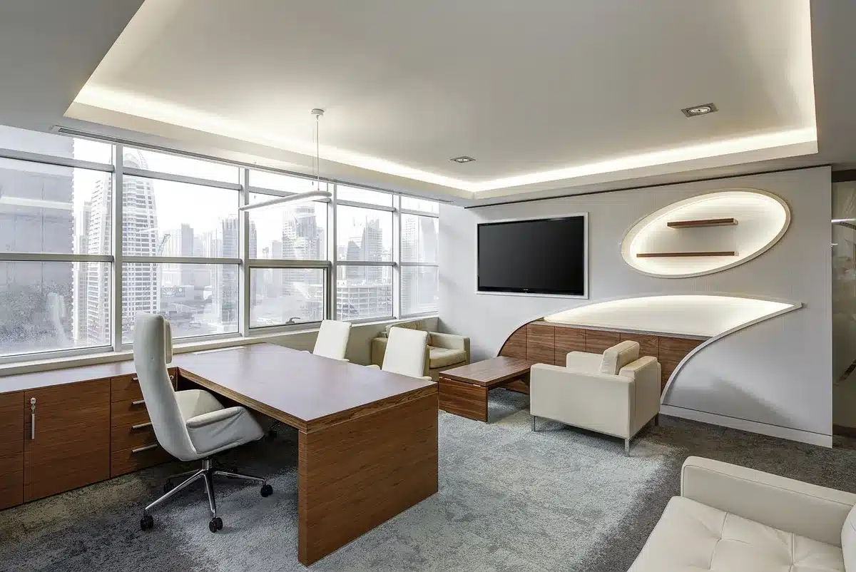 Empty modern meeting room with a central round table, flipchart and a laptop open showing a webinar interface