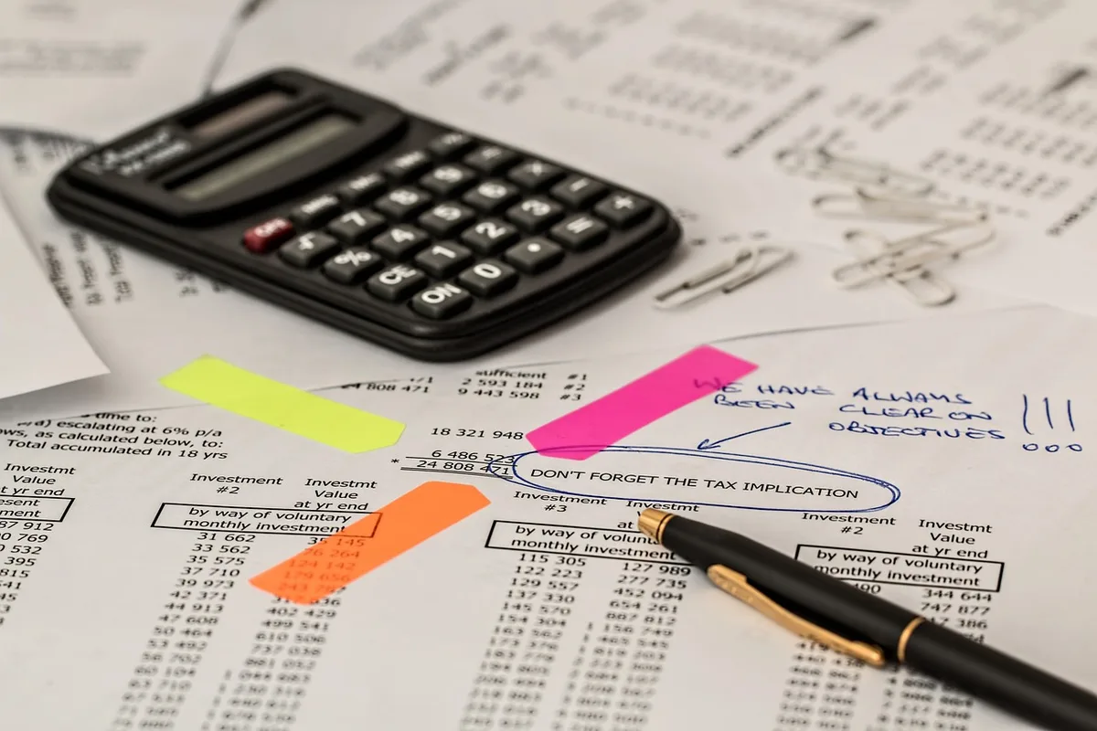 Calculatrice posée sur des feuilles avec chiffres de loyer estimé