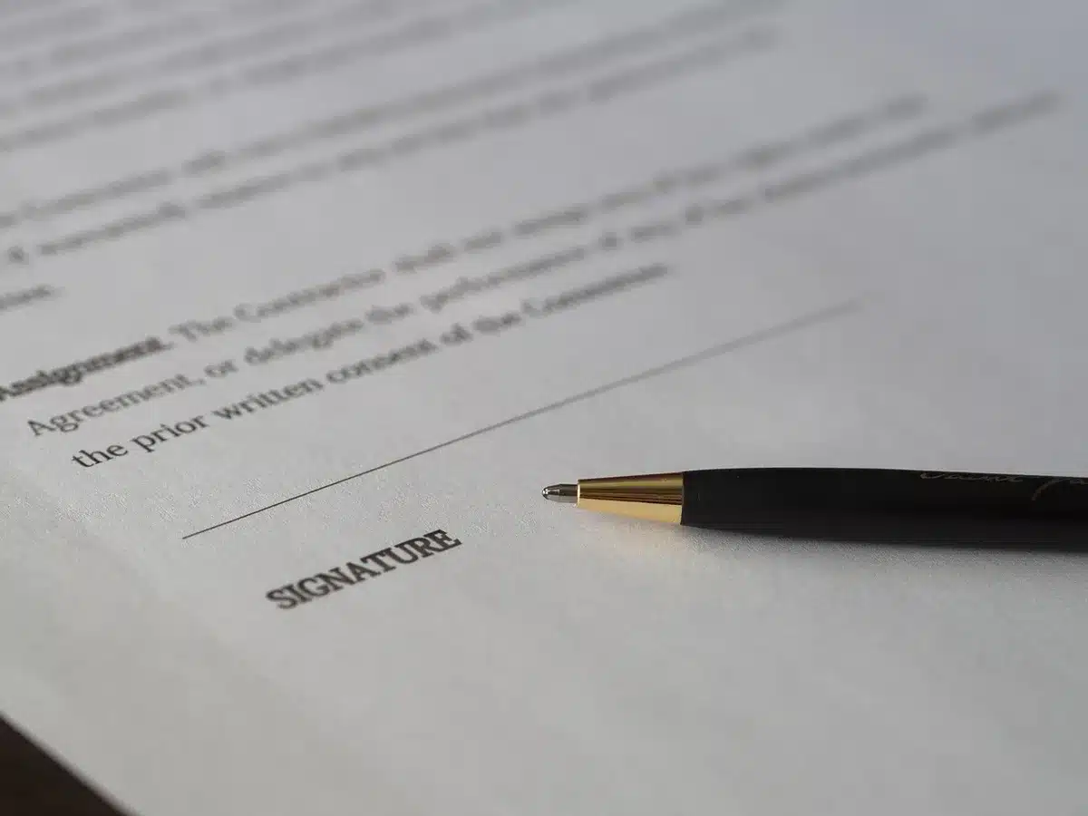 Mains tenant des documents immobiliers sur une table ensoleillée