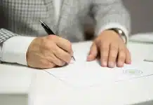 Quelle durée pour un arrêt maladie selon votre situation professionnelle ? Mains anonymes et documents médicaux sur un bureau inondé de lumière du jour