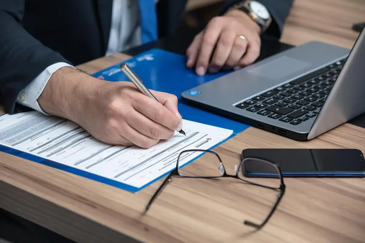 Personne range des documents administratifs et un checklist sur un bureau